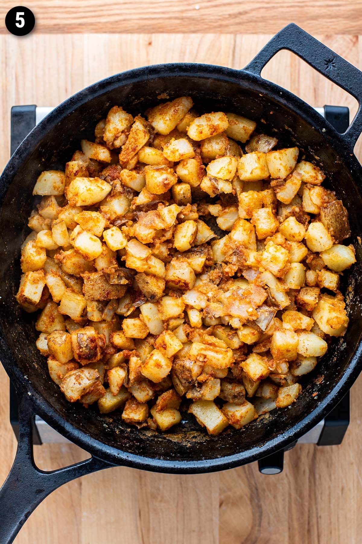 Golden home fries simmering in a cast iron skillet.