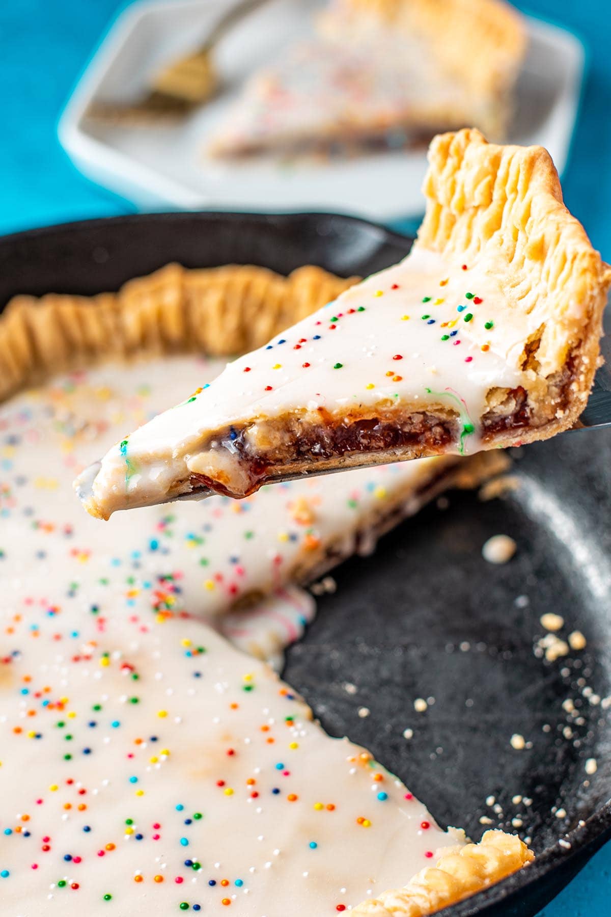 Lifting a slice of a skillet inspired strawberry Pop Tart pie out of a cast iron skillet.
