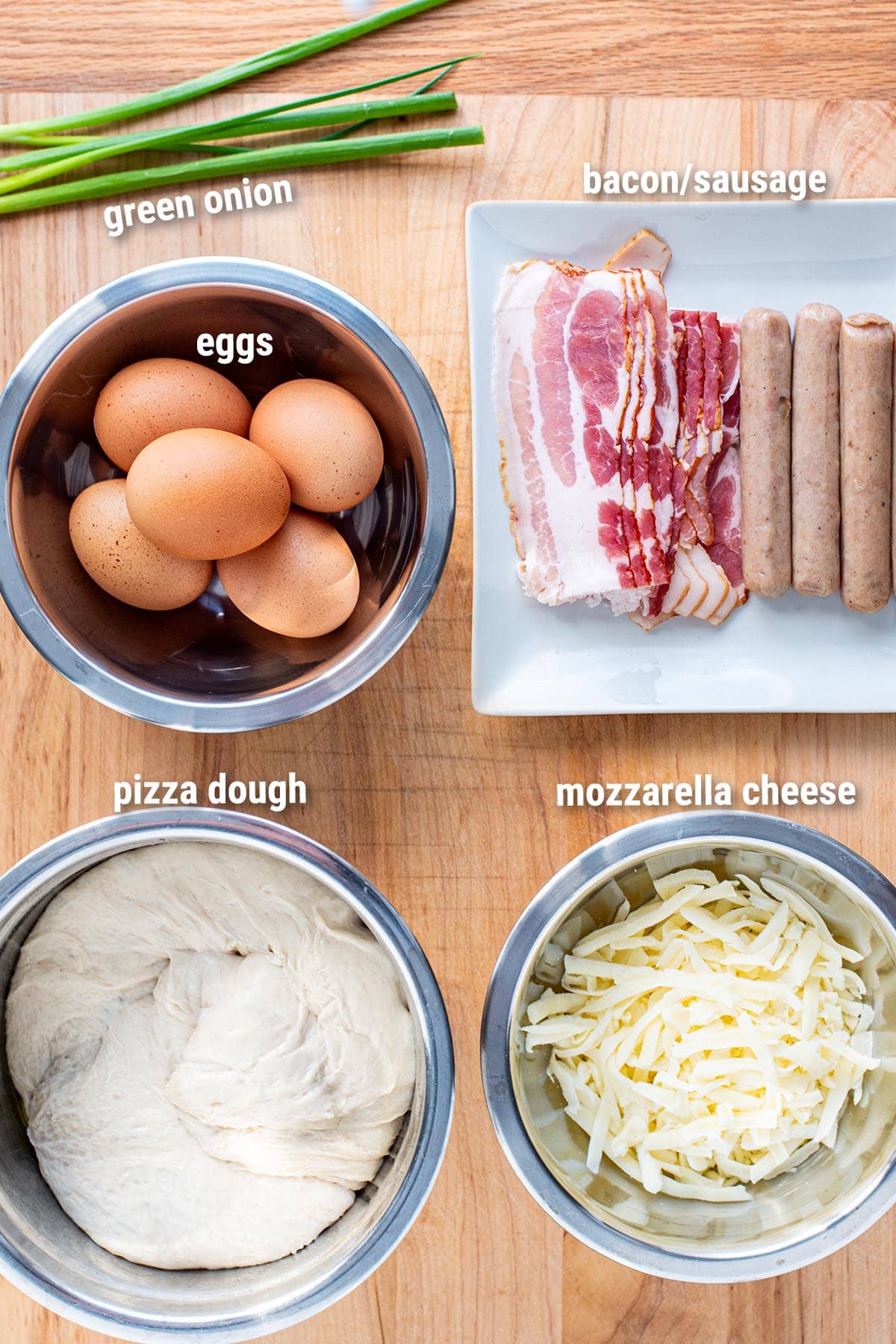 Raw, uncooked ingredients for skillet breakfast pizza laid out on a wooden cutting board.
