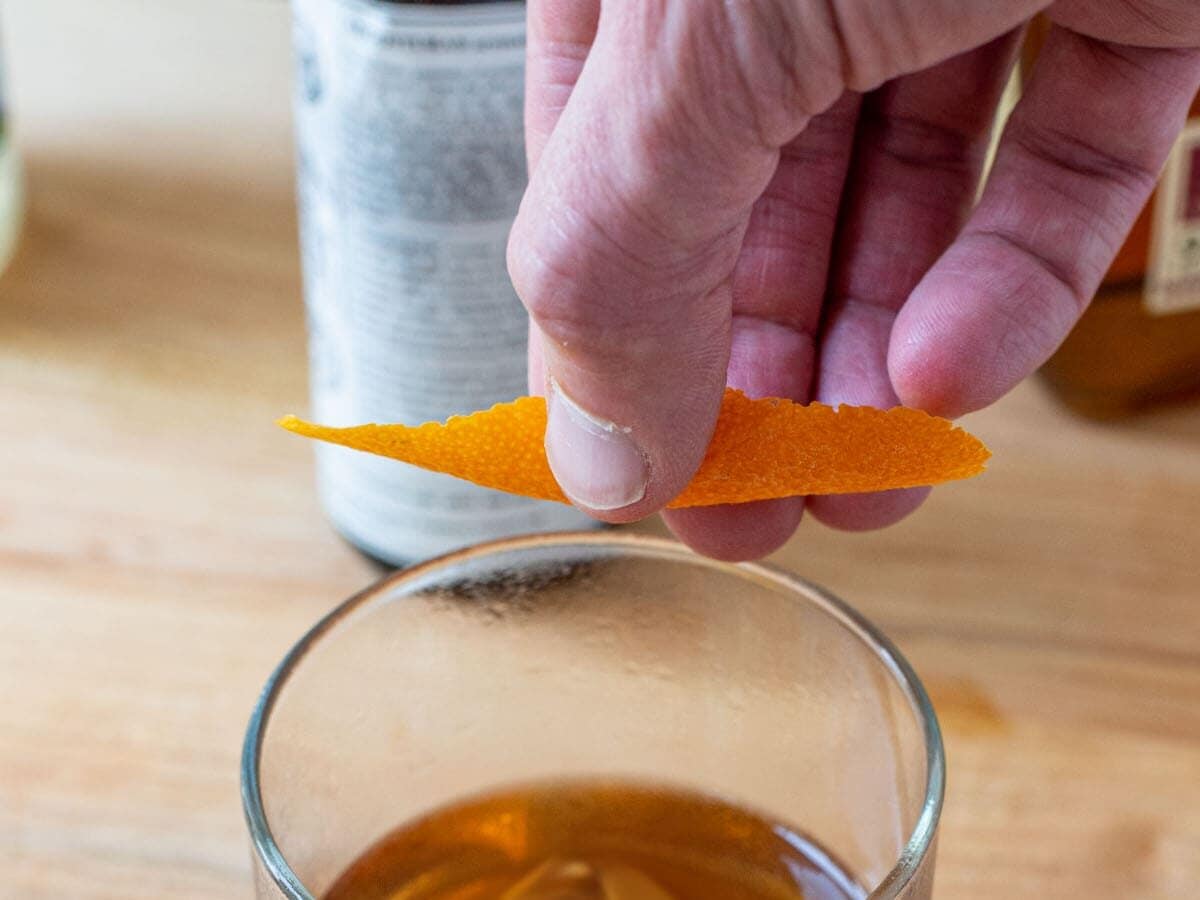 Expressing an orange peel over an Old Fashioned cocktail.