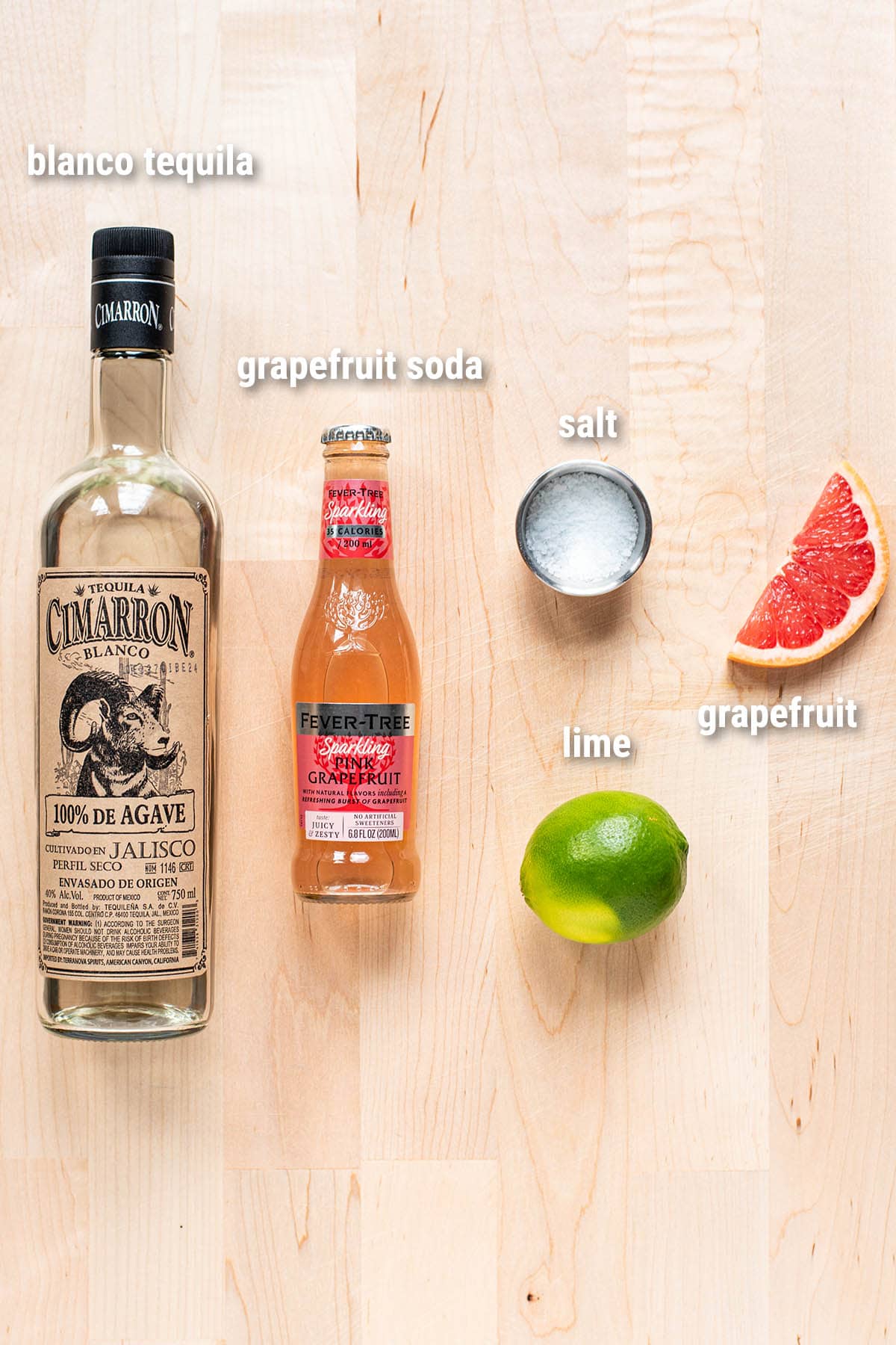 Paloma cocktail ingredients laid out on a wooden cutting board.