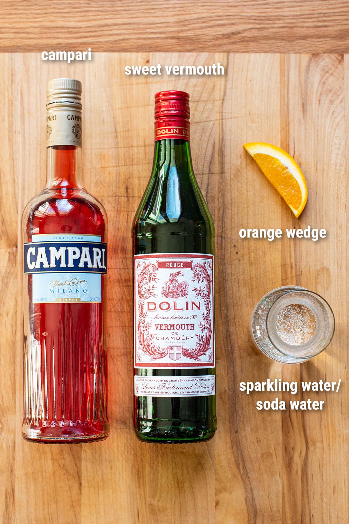 Americano cocktail ingredients laid out on a wooden cutting board.