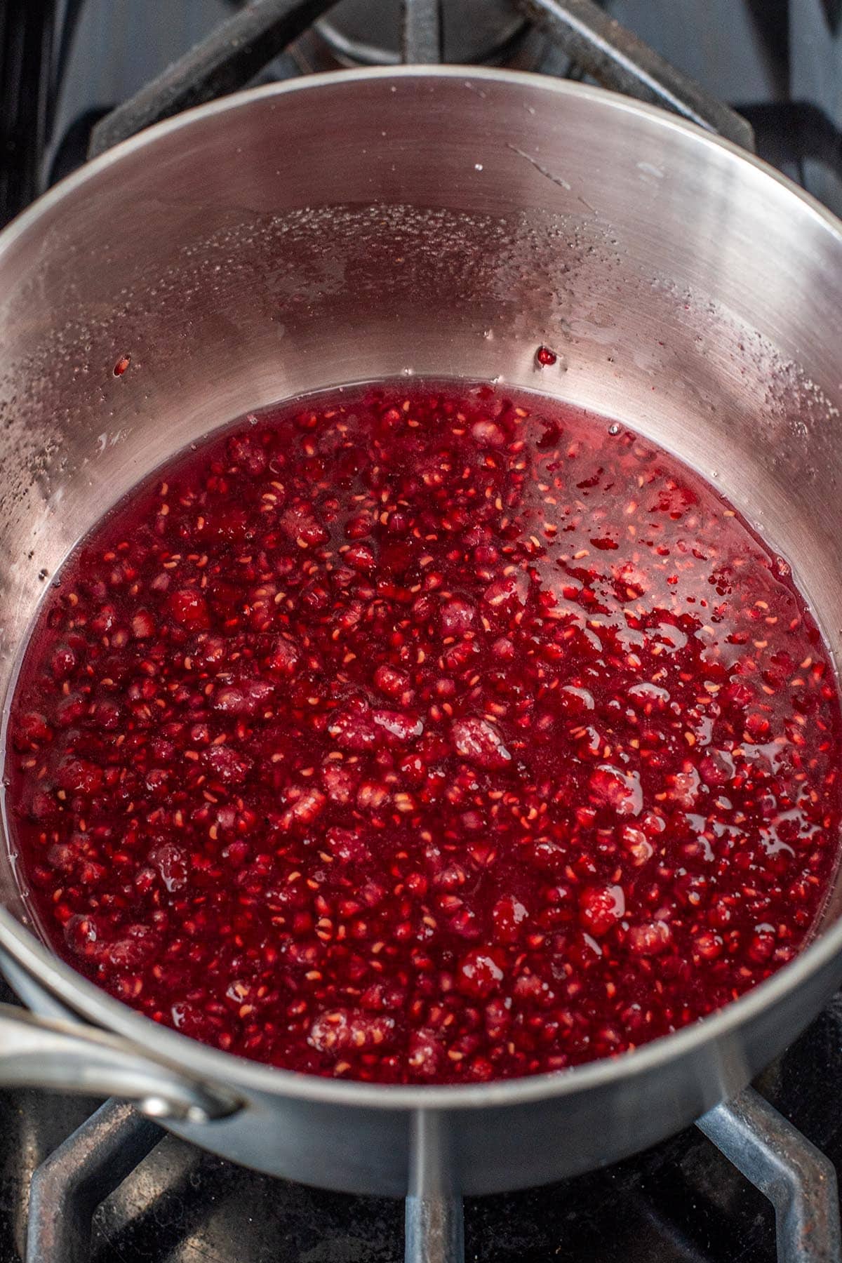 Heating raspberry syrup in a small saucepan.