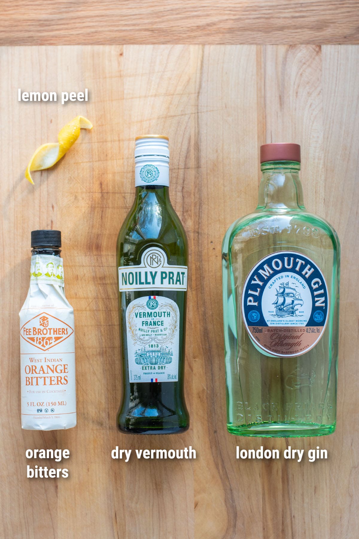 Classic gin Martini ingredients laid out on a wooden cutting board.