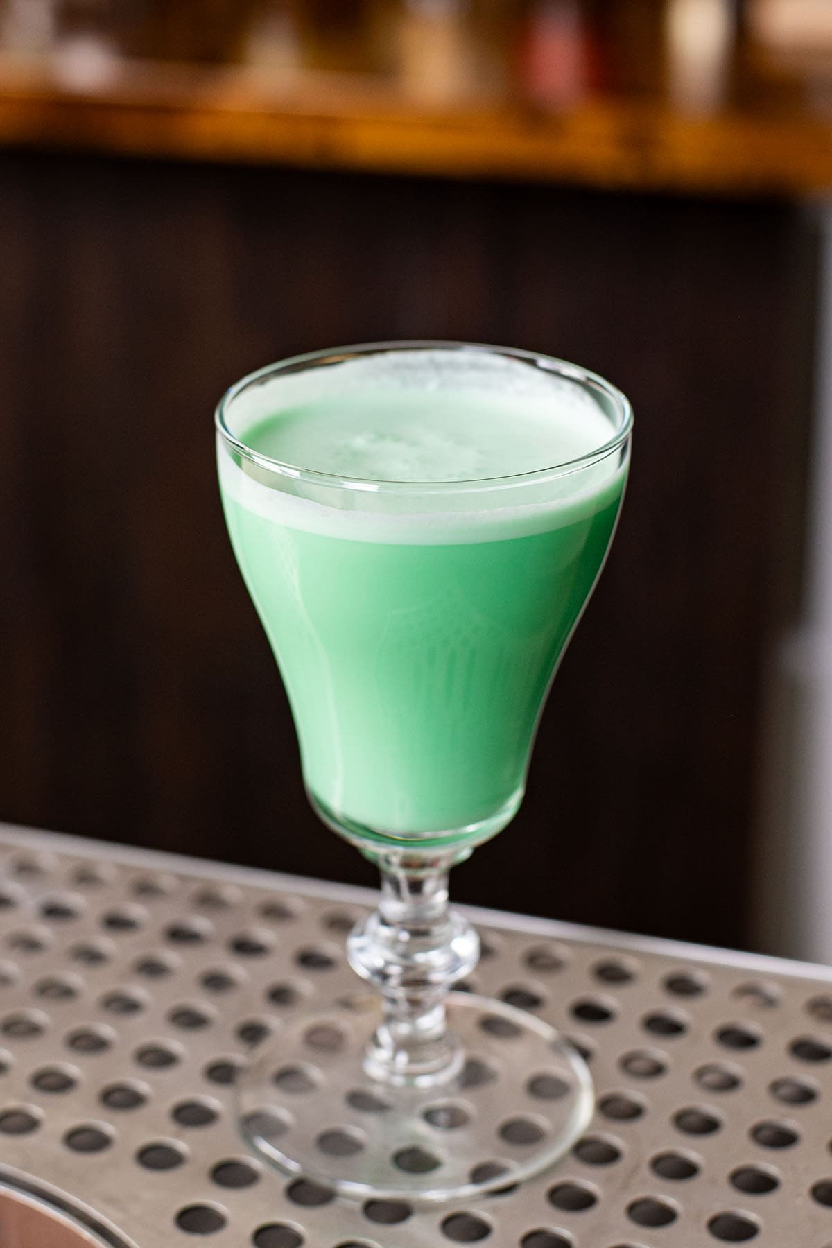 A minty green Grasshopper cocktail served in a short tulip glass.